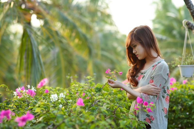 免费 女人穿着白色，粉色和绿色的花裙子，拿着粉红色的九重葛花 素材图片